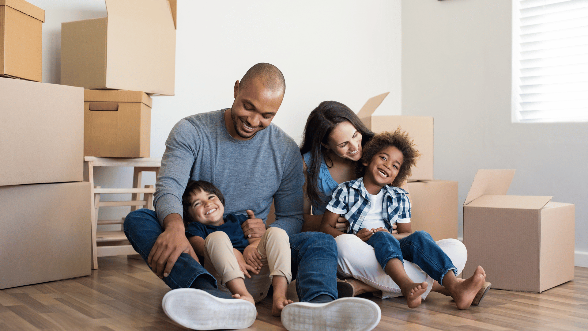 are you willing to relocate for work: a family sitting on the floor in an empty room with boxes around them
